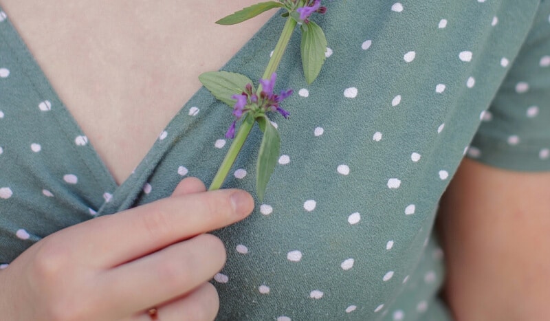 woman holding a flower close to the chest